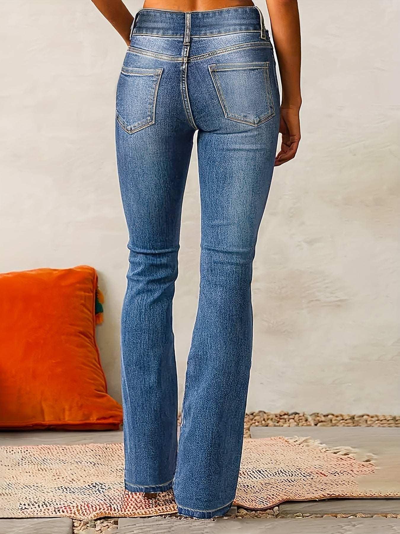 Person wearing blue jeans with a neutral background