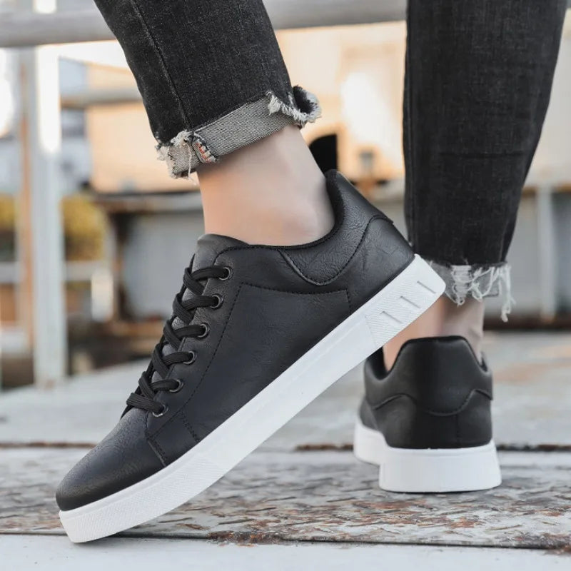 Black sneakers with white soles worn by a person on a blurred indoor background