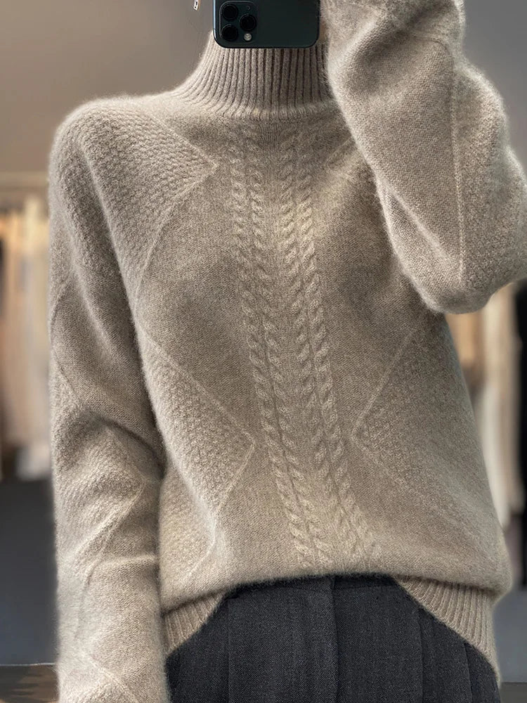 Beige sweater with cable knit pattern worn by a person, blurred background