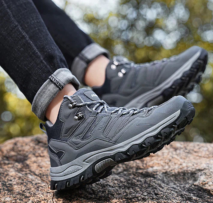 Gray hiking boots on a rocky surface with a blurred natural background