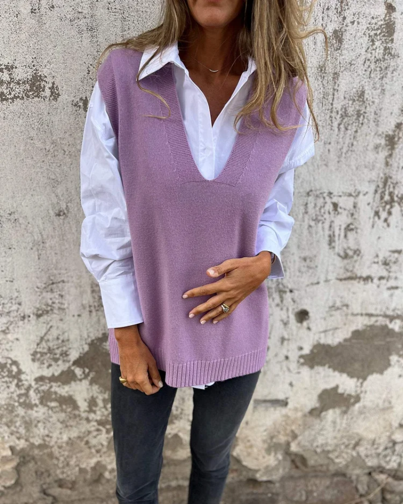 Person wearing a purple sweater vest over a white shirt with a neutral background