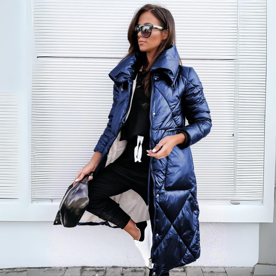 Woman wearing a long blue puffer coat against a white background