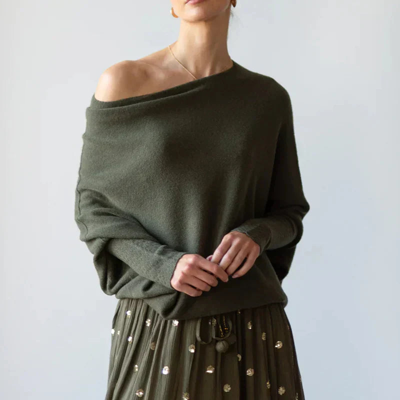 Person wearing an off-shoulder green sweater with a plain background