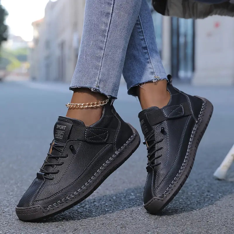 Black sneakers worn with light blue jeans on a blurred street background