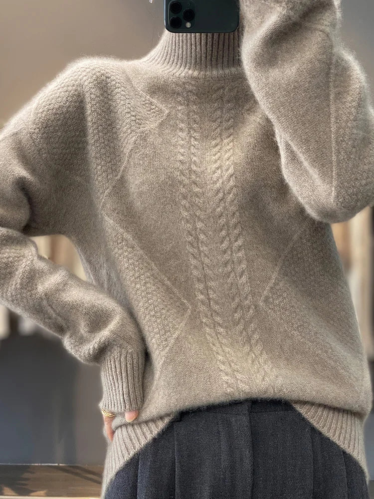 Beige sweater with cable knit pattern worn by a person, blurred background