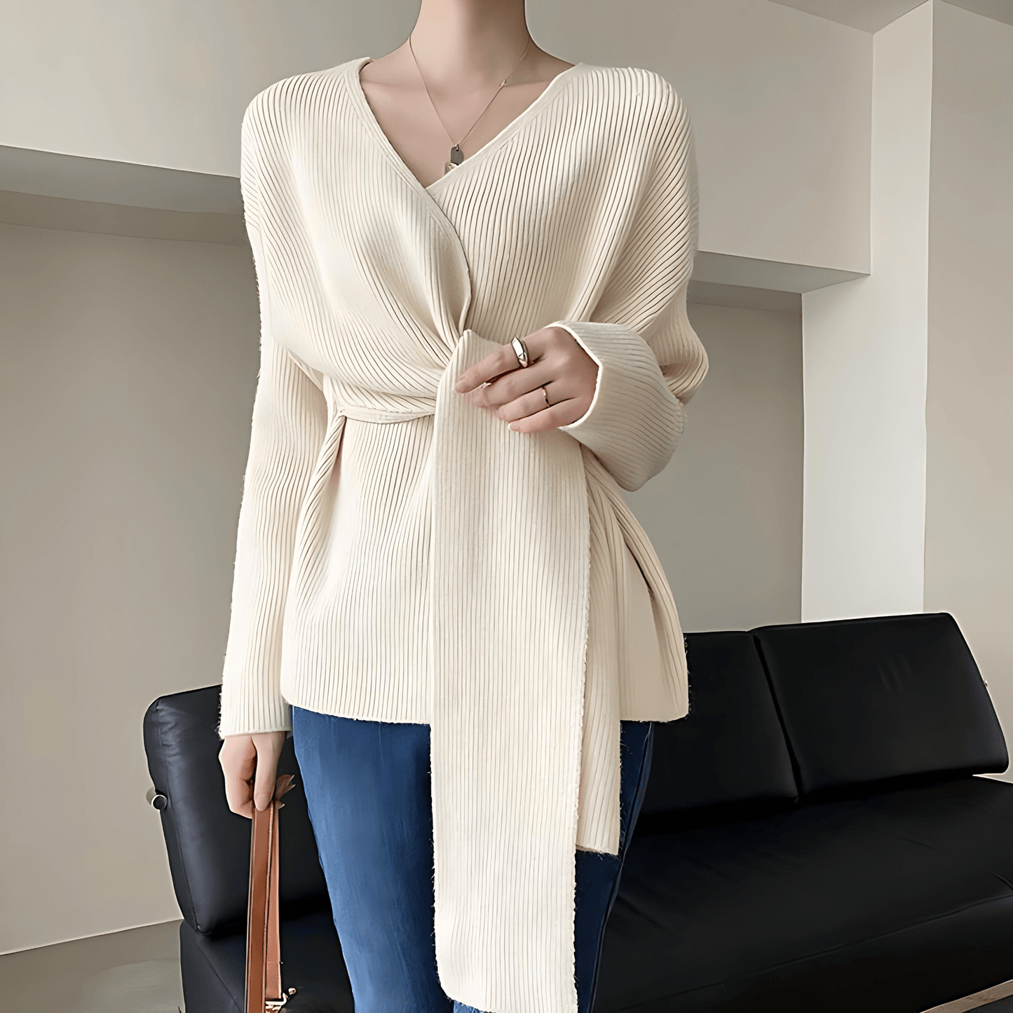 Mannequin wearing a cream ribbed sweater with a black sofa in the background