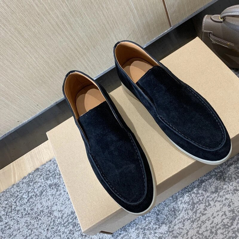Pair of navy loafers on a beige box with a neutral background