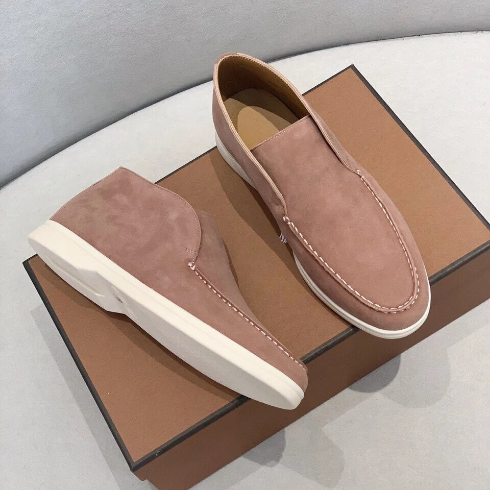 Pair of pink loafers on a brown box with a gray background