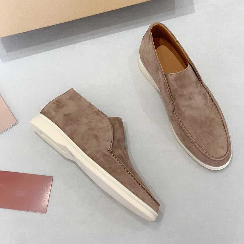 Pair of brown suede shoes on a light gray surface with a neutral background