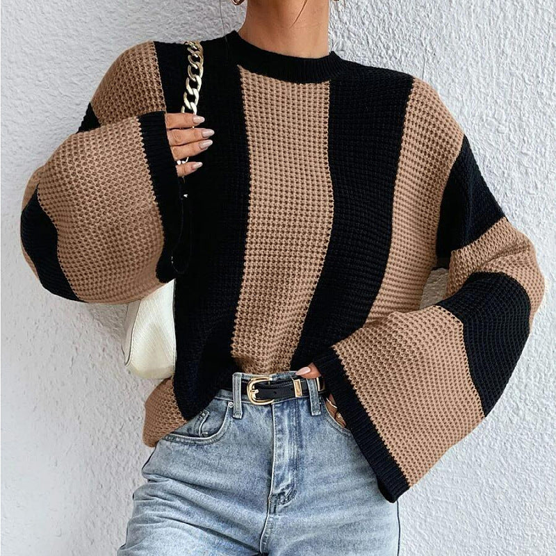 Person wearing a black and beige striped sweater with light blue jeans against a white background