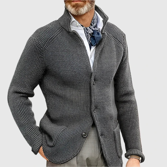 Man wearing a gray textured jacket with a white shirt and patterned scarf on a light gray background