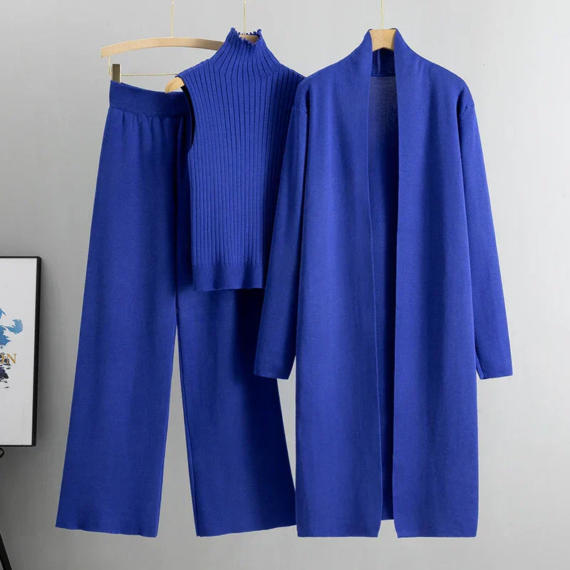 Blue outfit with a coat, pants, and top on hangers against a gray background