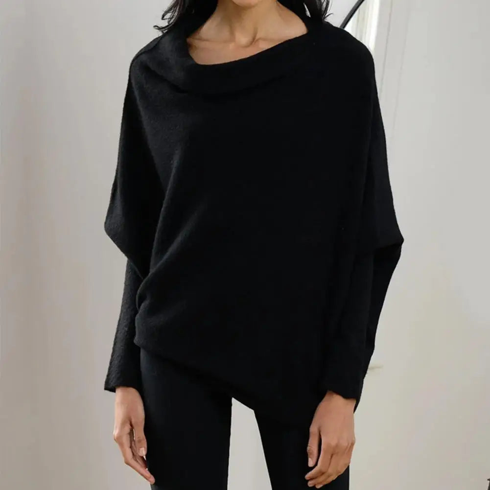 Person wearing a black poncho against a plain background