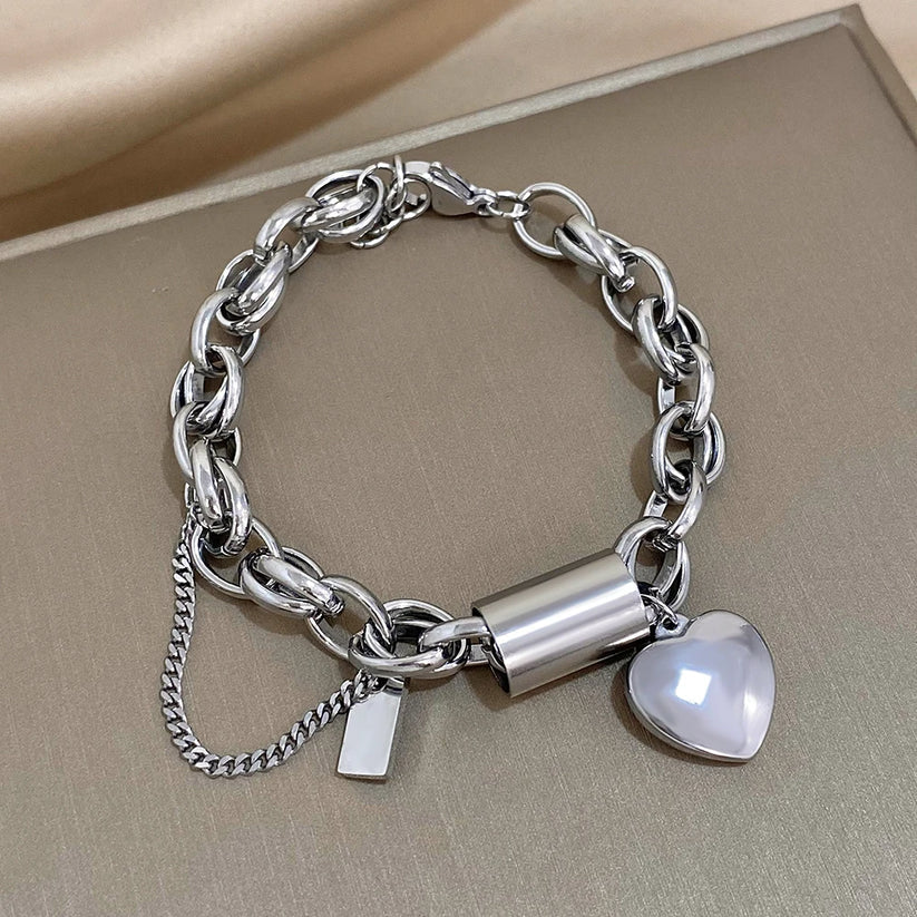 Silver chain bracelet with a heart-shaped charm on a beige surface