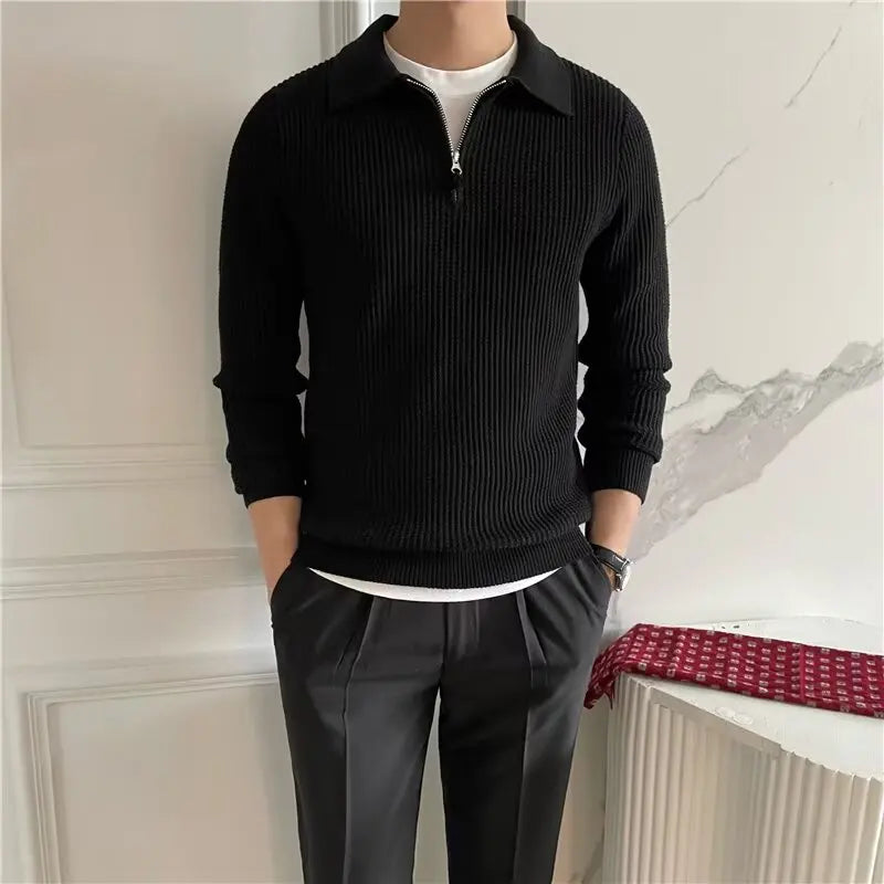 Person wearing a black sweater and gray pants against a neutral background