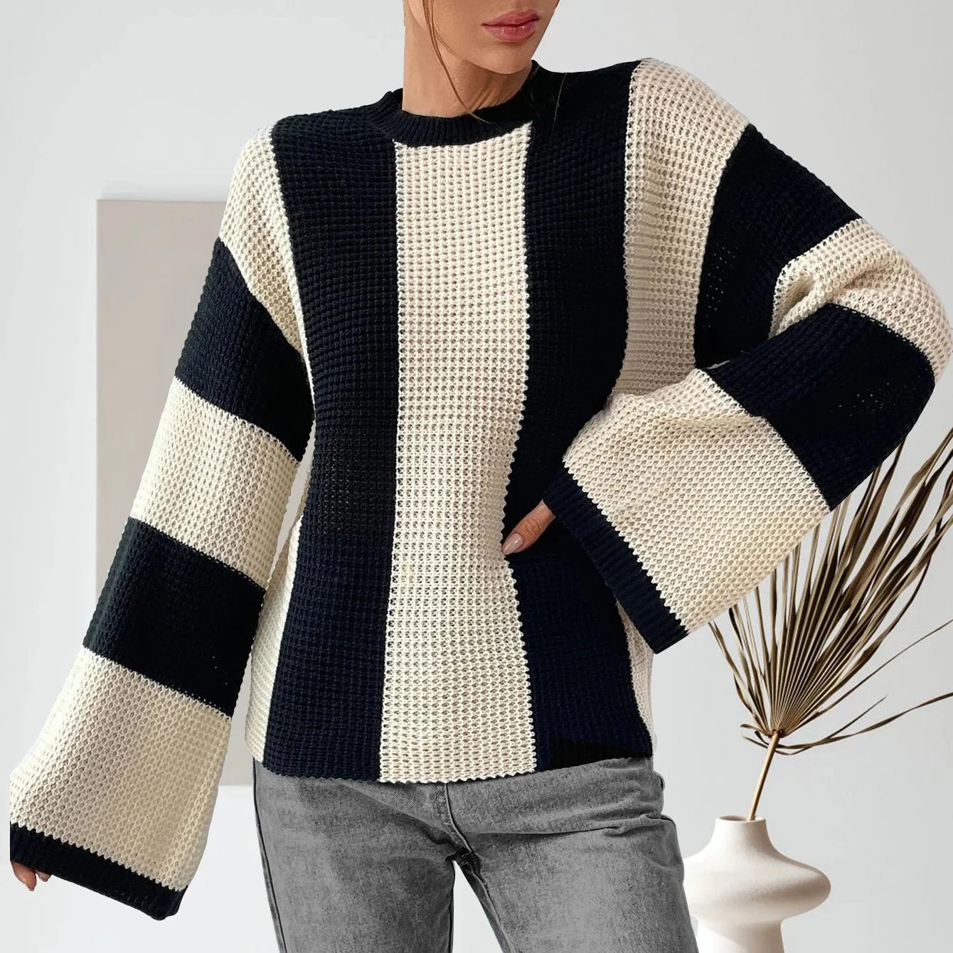 Person wearing a black and white striped sweater with a minimal background