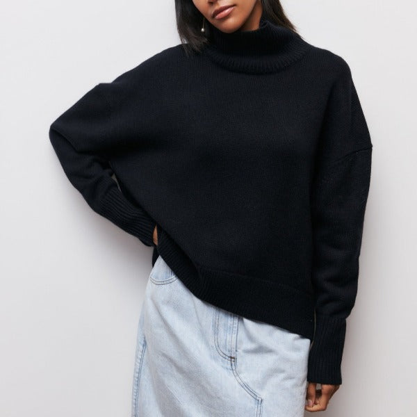 Person wearing a black turtleneck sweater and light blue jeans against a white background