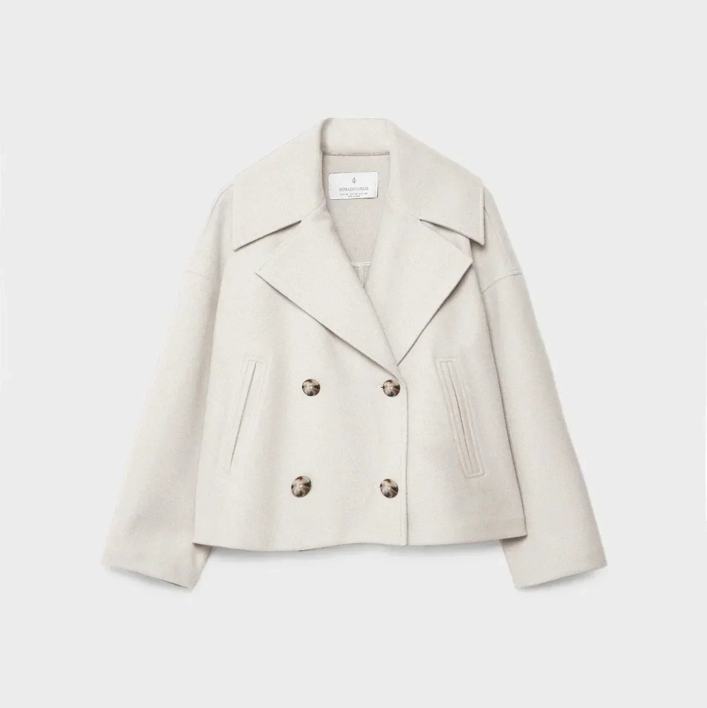 Beige blazer with button details on a light gray background