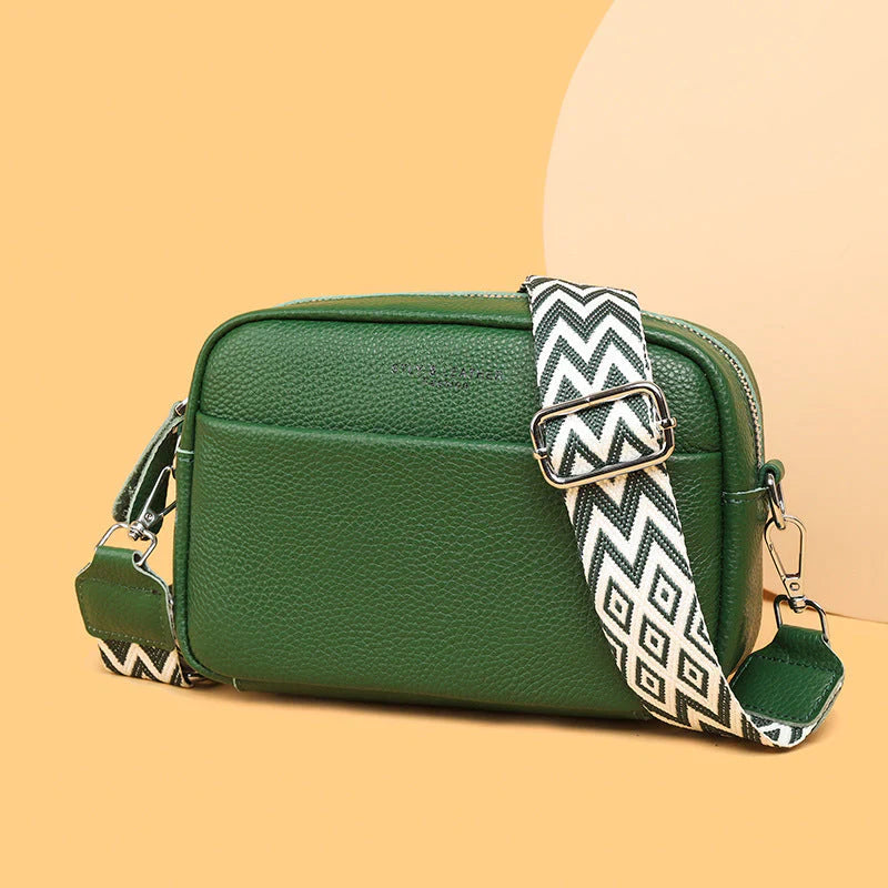 Green handbag with a patterned strap on a beige background