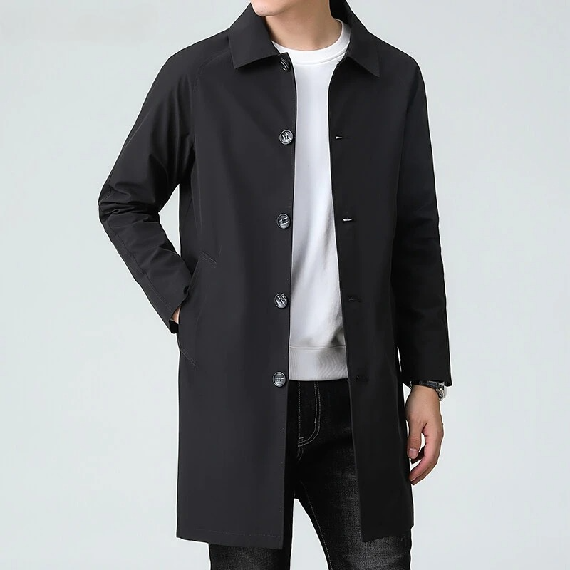 Person wearing a black coat over a white shirt on a light gray background