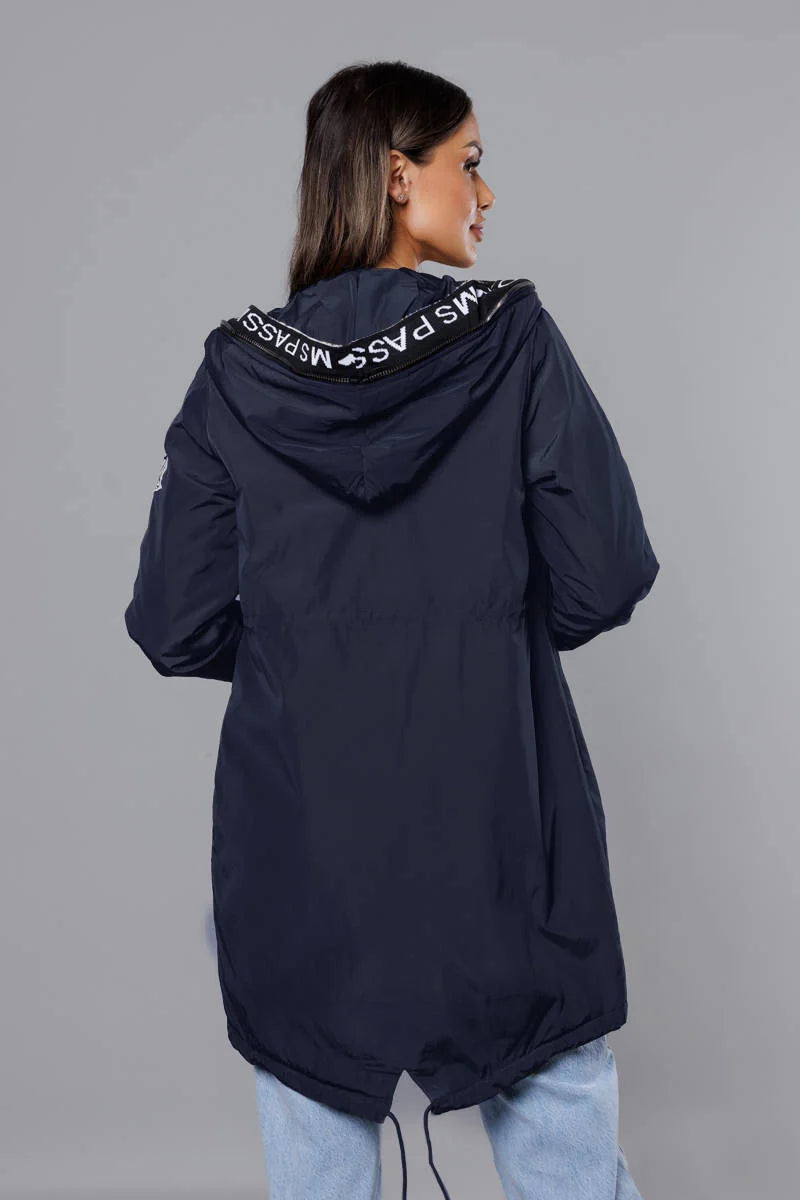 Person wearing a navy blue hooded coat with visible branding on a gray background