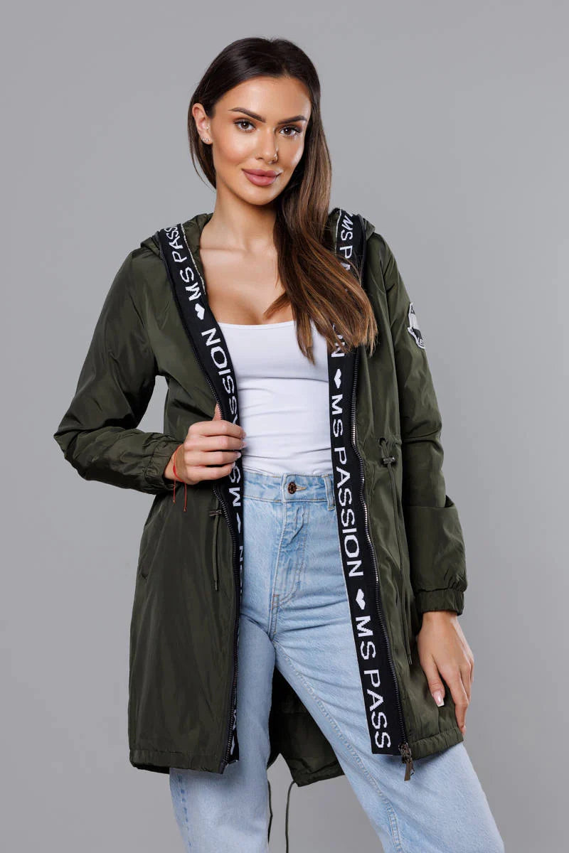 Woman wearing a green jacket with branding on a gray background