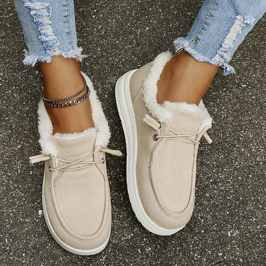 Beige sneakers with white fur lining worn on a concrete surface