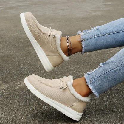 Beige winter boots with white fur lining worn by a person on a concrete surface.