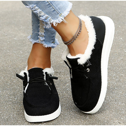 Black sneakers with white fur lining worn by a person on a concrete surface