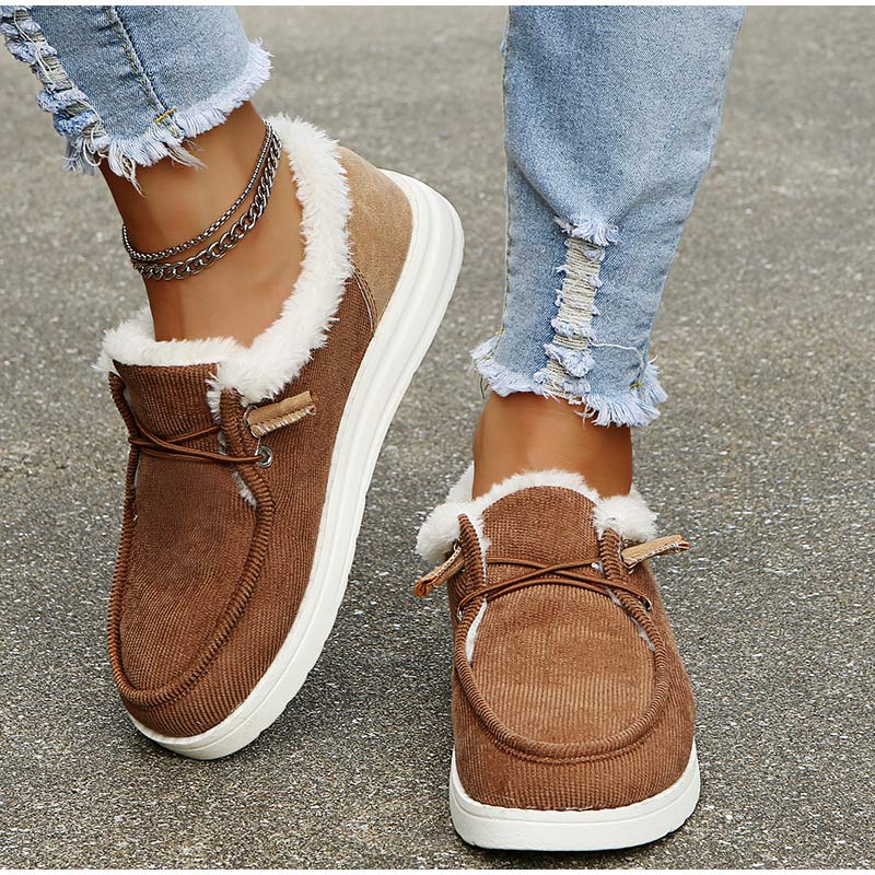 Brown winter boots with white fur lining worn by a person on a concrete surface.