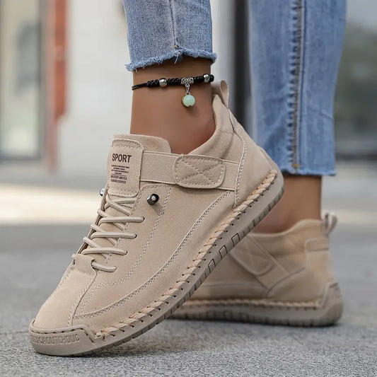 Beige sneakers worn with light blue jeans on a blurred street background