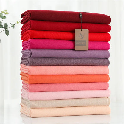 Stack of folded cloths in various colors with a brand tag on a white background
