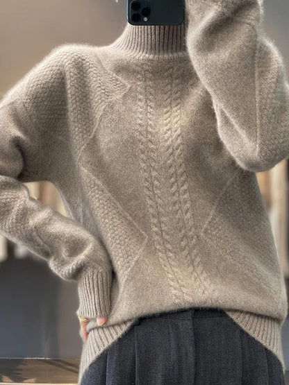 Beige sweater with cable knit pattern worn by a person, blurred background