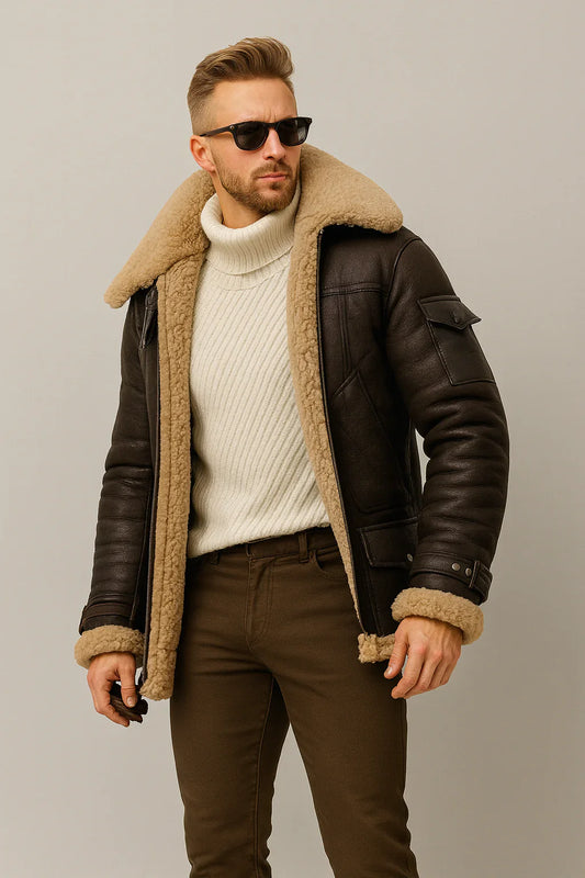 Man wearing a brown leather jacket with fur lining, white sweater, and brown pants on a plain background