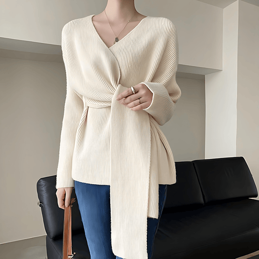 Mannequin wearing a cream ribbed sweater with a black sofa in the background