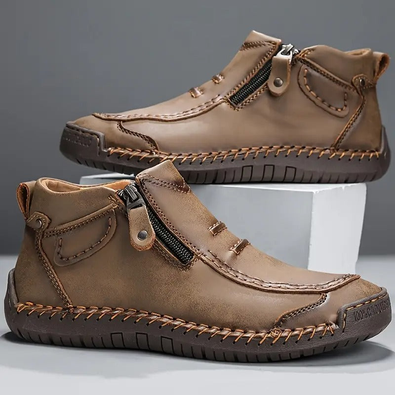 Pair of brown leather boots with zippers on a gray background