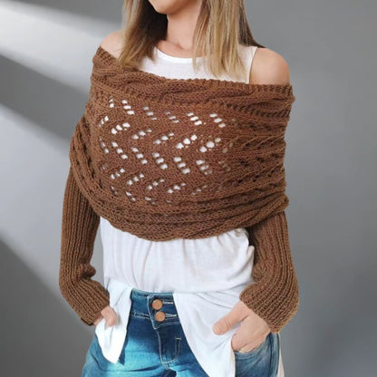 Person wearing a brown knitted shawl over a white top and blue jeans on a gray background