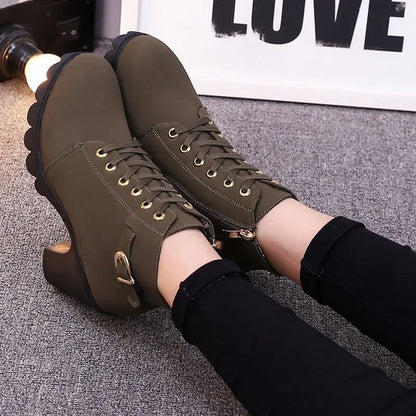 Brown high-heeled boots worn with black pants on a textured surface.