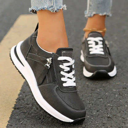 Black sneakers with white soles worn on a pavement surface
