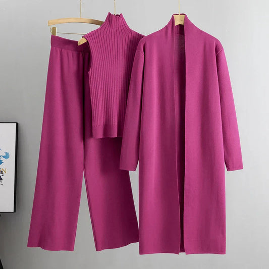 Purple outfit with a coat, pants, and top on hangers against a gray background