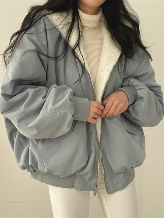 Person wearing a light gray jacket with a white interior on a plain background