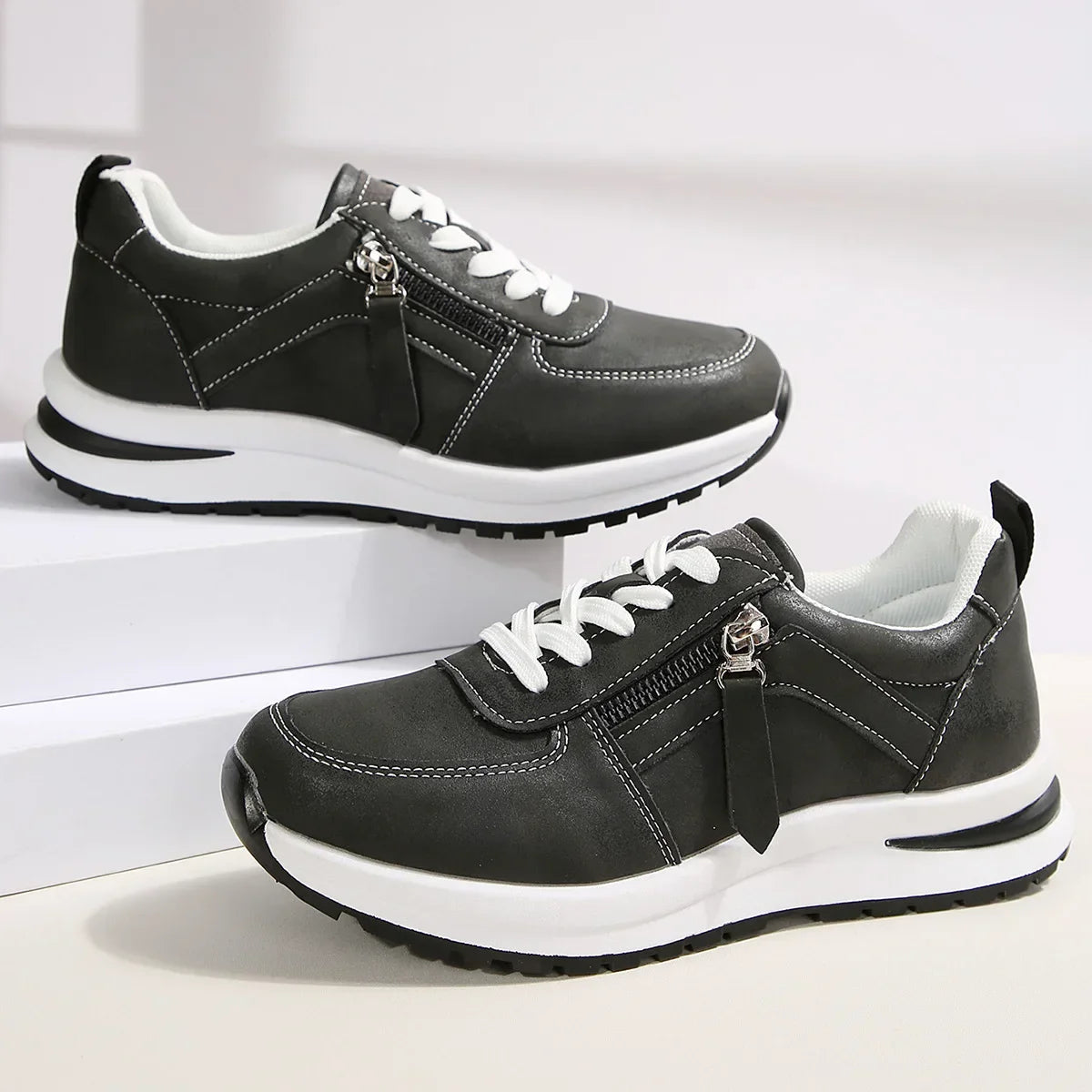 Black sneakers with white soles on a light gray background
