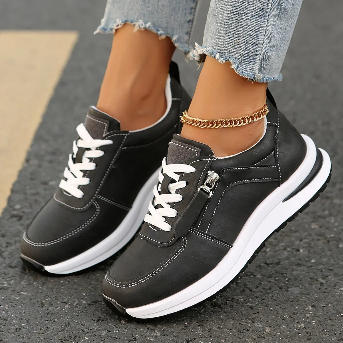 Black sneakers with white soles worn on a pavement surface