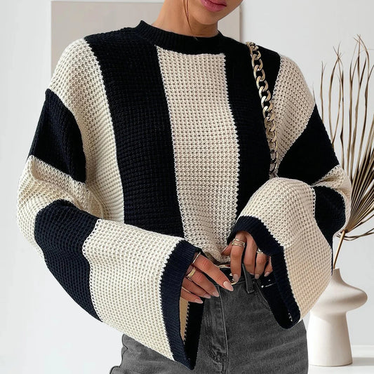 Person wearing a black and white striped sweater holding a phone.