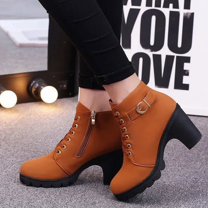 Brown ankle boots with black soles worn by a person, with a blurred background.