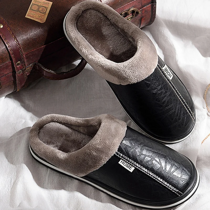 Pair of black slippers with gray fur lining on a white surface