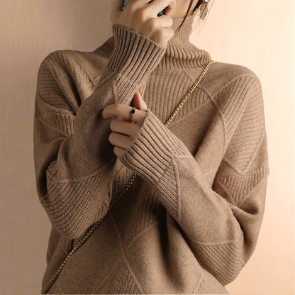 Person wearing a camel turtleneck sweater with dark pants