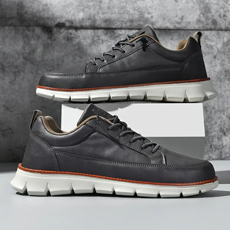 Pair of black leather shoes with white soles on a gray background